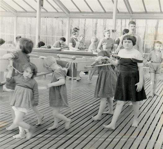 Kinderen leren lopen in een tredmolen in de wintertuin van de Willem van den Berghstichting.